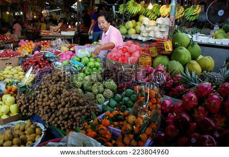 KANCHANABURI, THAILAND - December 28, 2010:  Woman selling a large variety of tropical fruits at the Fresh Market