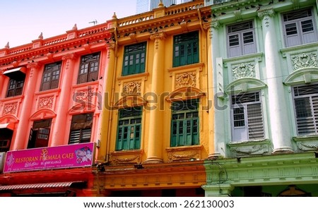 Kuala Lumpur, Malaysia - December 24, 2007: Pigeons hover on ledges above colonial-era buildings painted in bright colors in Little India