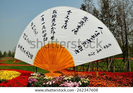 Qingbaijiang, China - October 28, 2010:  Chinese fan with quotations from Chairman Mao Zedong sits amidst displays of mums, Salvia, and Marigolds at the 2010 Phoenix Lake Park Chrysanthemum Exposition