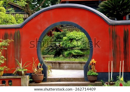 Emeishan, China - April 25, 2005:  Rounded moon gate leads to a courtyard garden at the ancient Bao Guo Buddhist Temple on Mount Emei