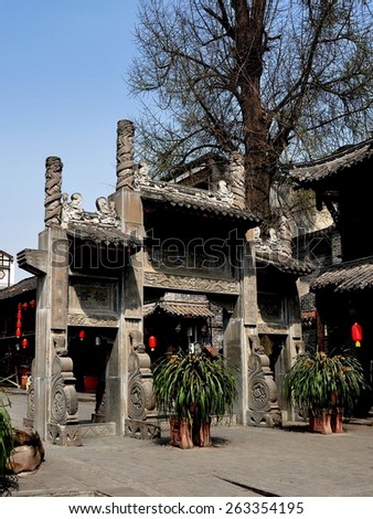 Jie Zi Ancient Town, China - March 6, 2013:  Ornate carved stone ceremonial entry gate leads into historic Gingko Square