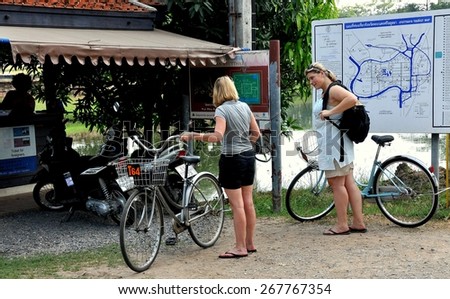 Ayutthaya, Thailand - December 20, 2010:  Two western women with rental bicycles touring the city\'s historic area stopping at Wat Phra Ram