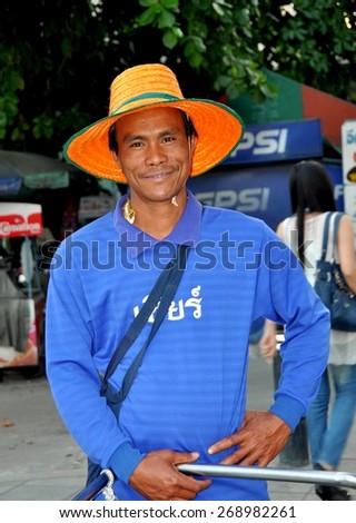 Bangkok, Thailand - January 16, 2011:  Smiling Thai man wearing an orange straw hat on Thanon Sathorn