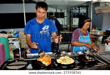 Bangkok, Thailand - January 17, 2012:  Husband and wife cooking food at their small restaurant at the MBK shopping complex outdoor food court