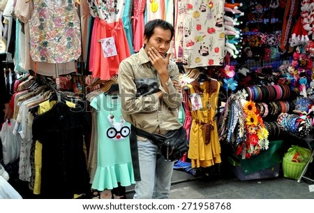 Bangkok, Thailand - December 23, 2013:  Vendor in a pensive mood at his outdoor women\'s clothing stand on Thanon Ratchaprasong