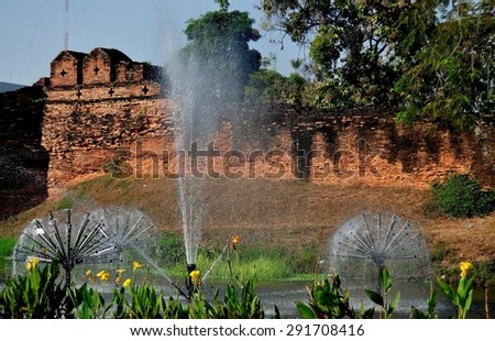 Chiang Mai, Thailand - January 1, 2013:  Ancient fortified brick city defense walls and  medieval moat with its splashing fountains
