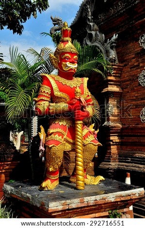 Chiang Mai, Thailand - December 19, 2012:  Fierce-looking red demon guardian figure flanks the entry gate to Wat Lok Molee