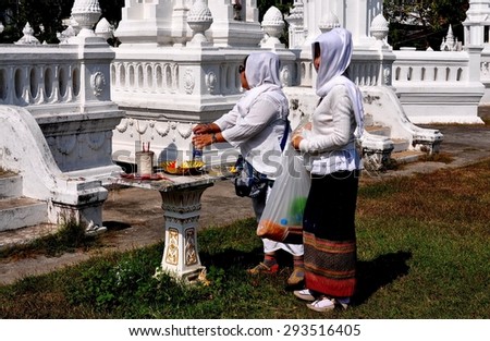 Chiang Mai, Thailand - January 5, 2013:  Two Women with heads covered with white scarves, at a shrine in front of reliquary tombs of northern Thai royalty at Wat Suan Dok