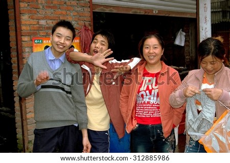Pengzhou, China - September 22, 2006:  Chinese family is all smiles in front of their shop in the Xiang district