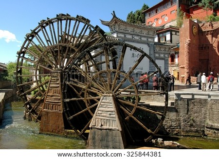 Lijiang, China - April 19, 2006:  Two traditional Chinese wooden water wheels churn water in a stream flowing through Si Feng Square