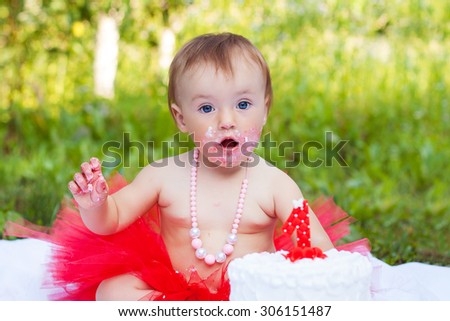 One year old girl eating her first cake and shows surprised emotion