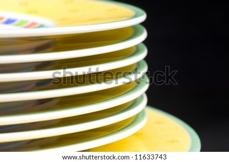 Dishware plates stacked closeup macro isolated on a black background as a diagonal image