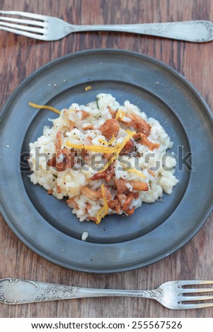 Risotto with chanterelle, parmesan and lemon zest on a tin plate.