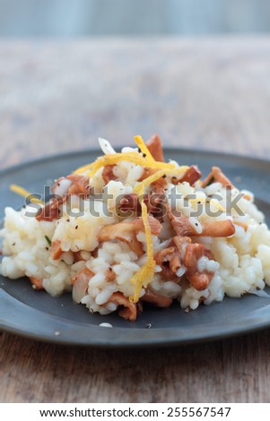 Risotto with chanterelle, parmesan and lemon zest on a tin plate.