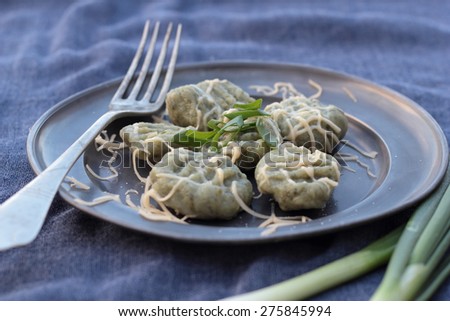 Gnocchi with spinach and grated cheese on a tin plate.