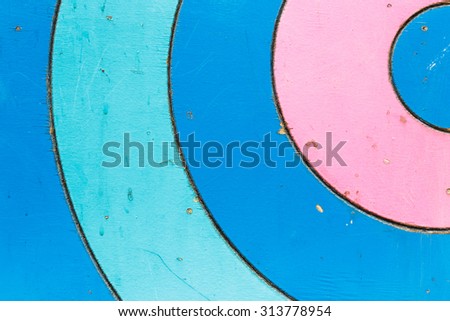 circle  wooden panel from children playground. Obsolete timbered surface. Blue pink painted wood