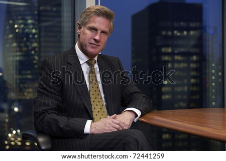 Business man sitting at table in boardroom looking at camera