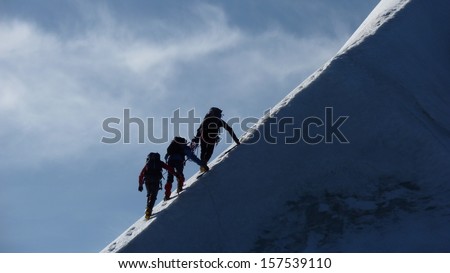 Rope team climbing icy mountain ridge