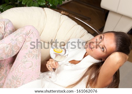 Closeup fashion portrait of young woman sitting relaxed on comfortable sofa and drinking water