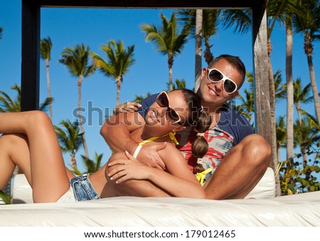 Sexy and attractive couple lying on luxury white sun bed on a tropical garden, near a swimming pool.