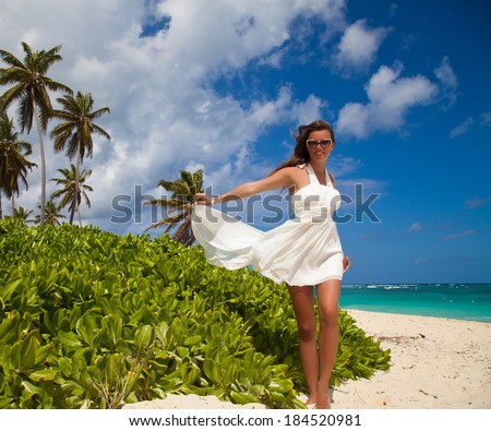 Sexy brunette woman in white wedding dress on the Caribbean beach. Summer vacation