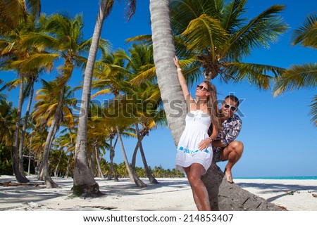 Happy young romantic couple in love relaxing on luxury private Caribbean beach under palm tree