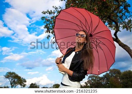Happy young fashion woman with umbrella under the summer rain. Beautiful girl enjoying rainy summer day looking up at sky smiling cheerful.