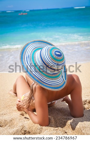Sun kissed woman relaxing on the Hawaiian beach in straw hat and bikini. Fresh air, summer sun and total relaxation