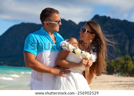 Shot of young couple enjoying beach getaway, looking at each other affectionately. Couple in love, summer luxury vacation in Hawaii. Travel holidays concept.