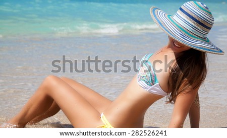 Colourful shot of a beautiful woman on the beach in Hawaii. Girl lying and looking away. Vacations And Tourism Concept. Summer luxury vacation in Hawaii.