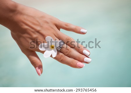 Cropped view of a elegant  female hand with a diamond ring and bright stylish manicure with colored nail.