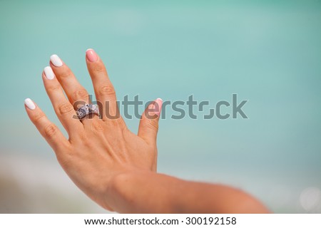 Cropped view of a elegant  female hand with a present diamond ring and bright stylish manicure with colored nail.