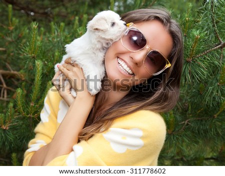 Attractive young female outside with her puppy. Cute puppy licking its attractive young female owner's face.