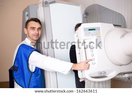 A male doctor operation an x-ray machine in a clinic medical lab with a patient