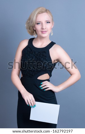 Fashion blond woman holding empty billboard in hands with bright makeup and manicure in studio