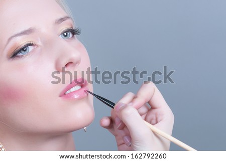 High fashion look glamour sexy woman makeup artist applying bright makeup  brush near face in studio