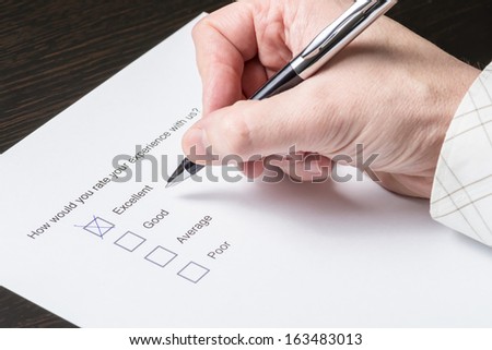 Close up of the hand of a business man filling out a customer satisfaction survey.
