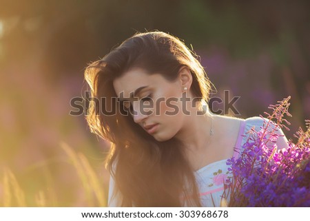 Beautiful young girl, happy, holding lavender in a field on sunset. walking field. Soft focus, close-up