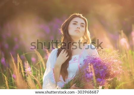 Beautiful young girl, happy, holding lavender in a field on sunset. walking field. Soft focus, close-up