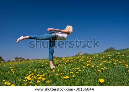 female practicing yoga on a flowery meadow