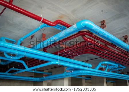 Red fire water pipes on the concrete wall in the condo building.Installation of drainage pipes in the building.Sanitary system of a condominium.water piping system install with the concrete ceiling.