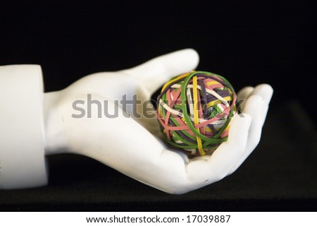 White hand holding rubberband ball