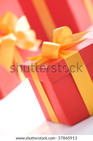 Cute red gift boxes with gold ribbon on white background. Photo taken at an angle