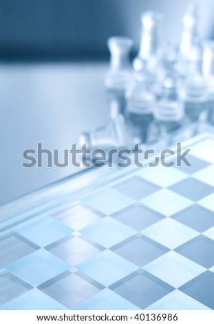 White transparent pieces of chess on chess board made of glass. All in blue ambient light