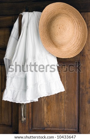 White cotton dress and straw hat on antique cabinet