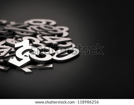 closeup image with pile metal numbers on black background, space for your text