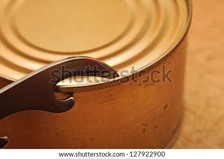 The old tin opener opening a can on wooden table