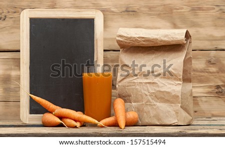 Healthy food - carrots and carrots juice with paper bag on wooden background