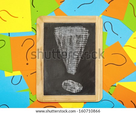 Pile of colorful paper notes with question marks and small blackboard with exclamation mark