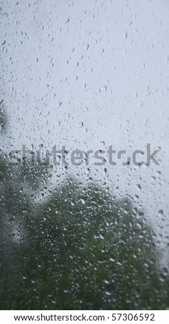 raindrops collecting on a window on a gloomy and rainy day.